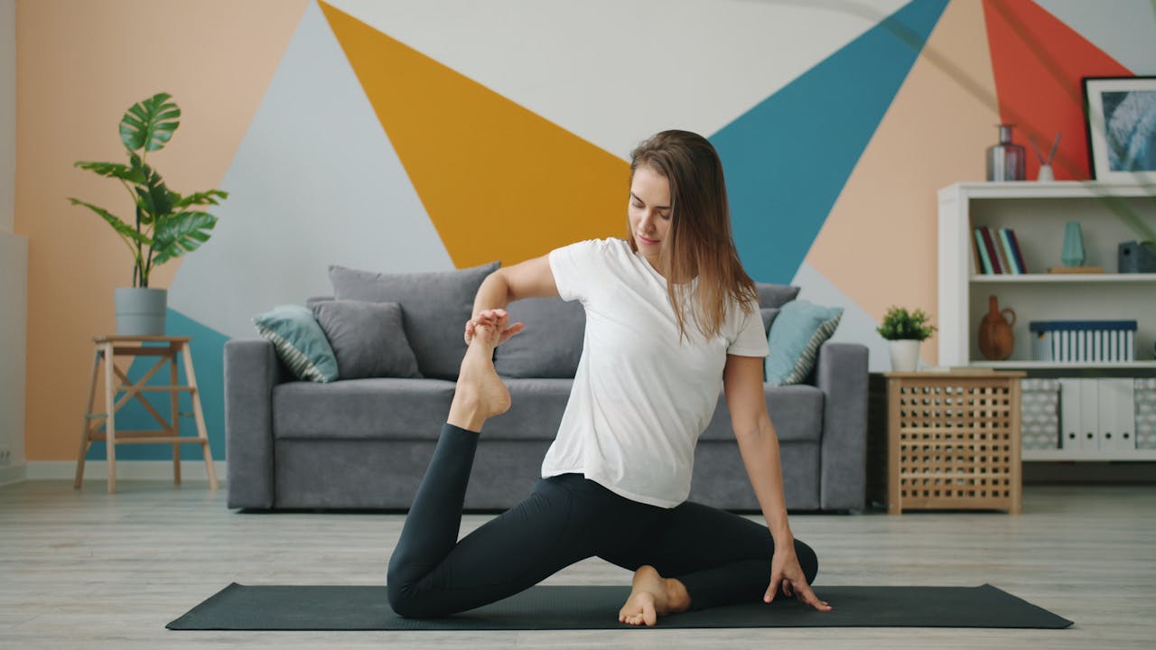 A woman performs yoga on a mat in a colorful, modern living room setting.